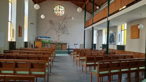 Kirche Britz Dorf mit spitzem Turm und Uhr, umgeben von kahlen Bäumen, im Vordergrund ein zugefrorener See