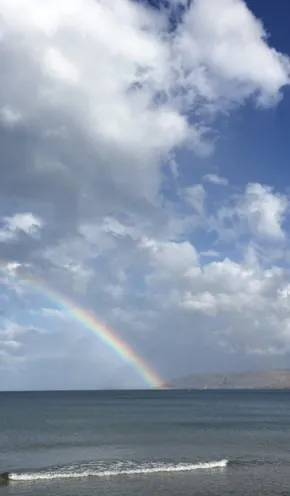 Meer ind die Wolken übergehend, mit einem Regenbogen